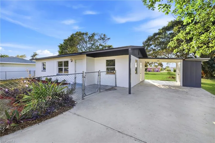 View of front facade with a gate, an attached carport, stucco siding, and concrete driveway