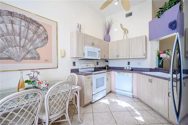 Kitchen featuring light  cabinetry, double sink, white appliances, high vaulted ceiling, and ceiling fan