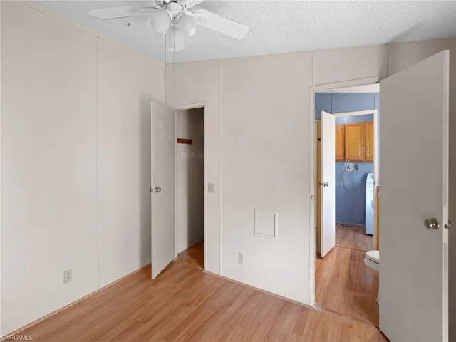 Unfurnished bedroom featuring wood finished floors, a textured ceiling, ceiling fan, washer / clothes dryer, and a closet