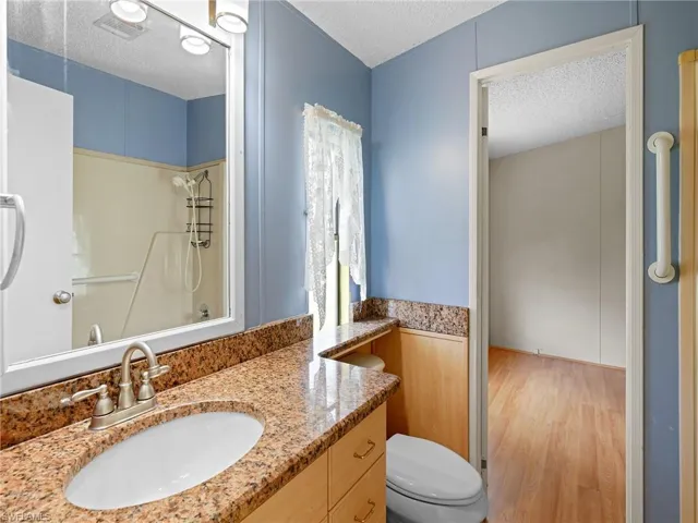 Full bathroom featuring a textured ceiling, wood finished floors, vanity, and shower / bath combination