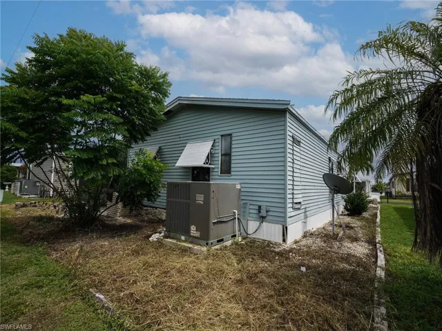 View of property exterior with a central air condition unit and a lawn