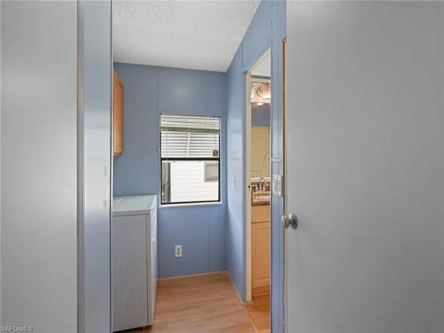 Laundry area featuring cabinet space, light wood-style floors, washer / dryer, and a textured ceiling