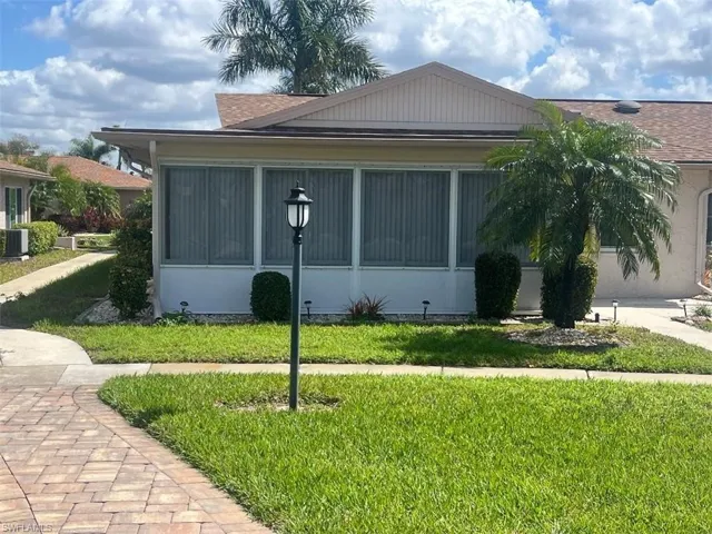 View of side of home with a shingled roof and a yard