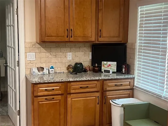 Kitchen with wood finish cabinetry, light stone counters, and decorative backsplash