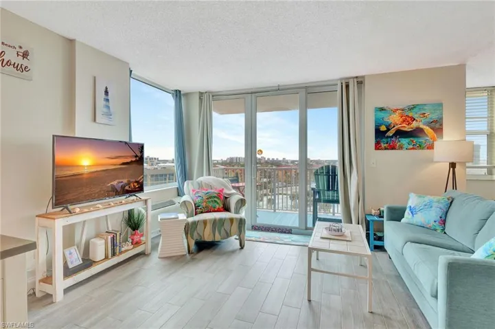 Living room with floor to ceiling windows, a textured ceiling, and light wood finished floors