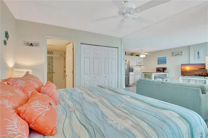 Bedroom with connected bathroom, a ceiling fan, freestanding refrigerator, and a closet