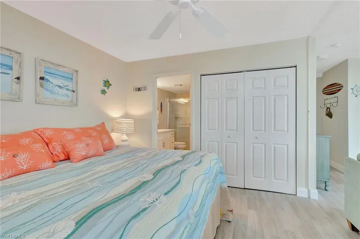 Bedroom featuring a closet, light wood-style floors, ensuite bath, and ceiling fan