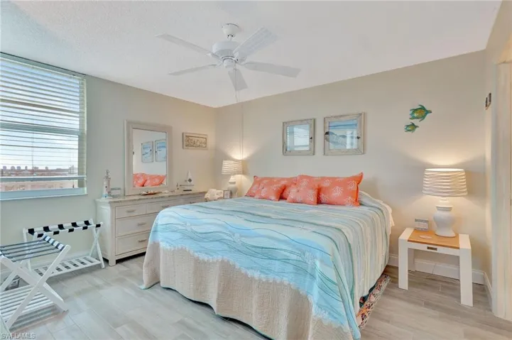 Bedroom featuring a closet, light wood-style floors, ensuite bath, and ceiling fan