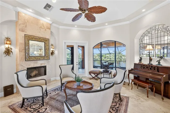 Living room featuring ornamental molding, a fireplace, ceiling fan, a high ceiling, and french doors