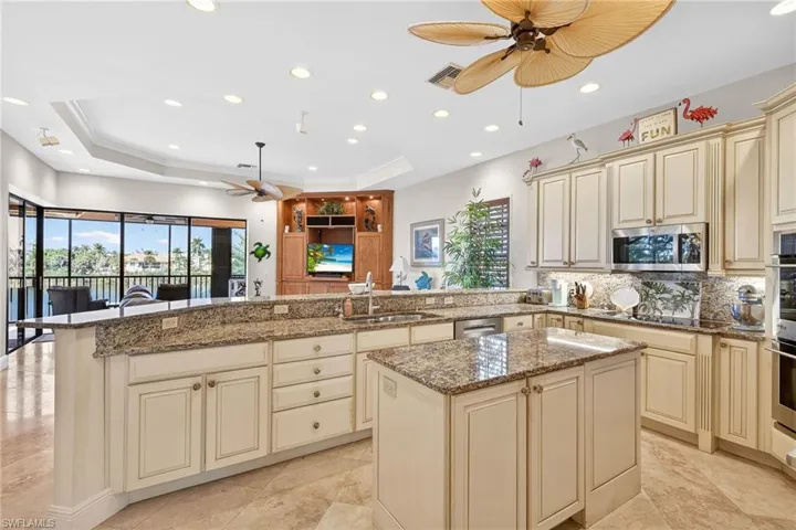 Kitchen featuring cream cabinets, ceiling fan, dark stone counters, a center island, and recessed lighting