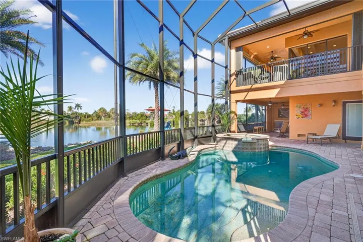View of swimming pool with a lanai, a patio, a sunroom, a pool with connected hot tub, and a balcony