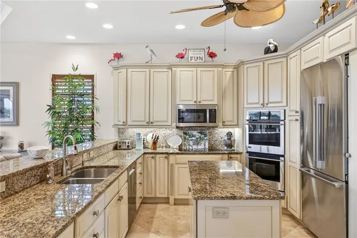 Kitchen with cream cabinets, dark stone countertops, stainless steel appliances, and recessed lighting