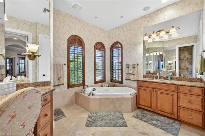 Primary bathroom with a bath, wallpapered walls, vanity, and recessed lighting