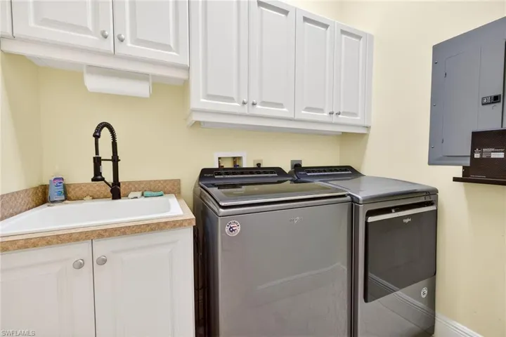 Laundry area featuring electric panel, washer and clothes dryer, and cabinet space