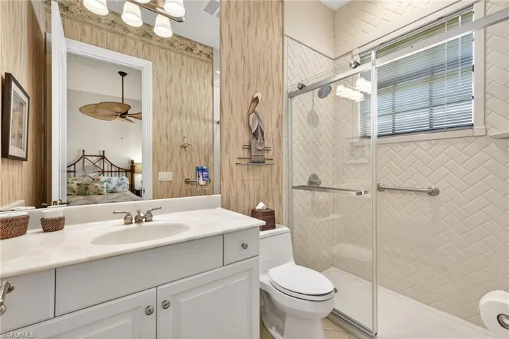 Full bath with ensuite bath, vanity, a shower stall, and ceiling fan