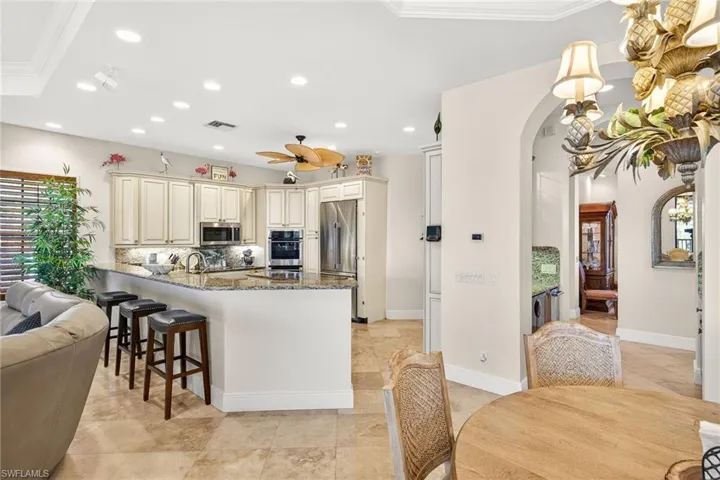 Kitchen with cream cabinets, plenty of natural light, dark stone counters, a breakfast bar, and ornamental molding
