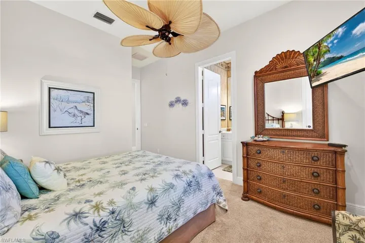 Bedroom featuring light colored carpet, a ceiling fan, and ensuite bath