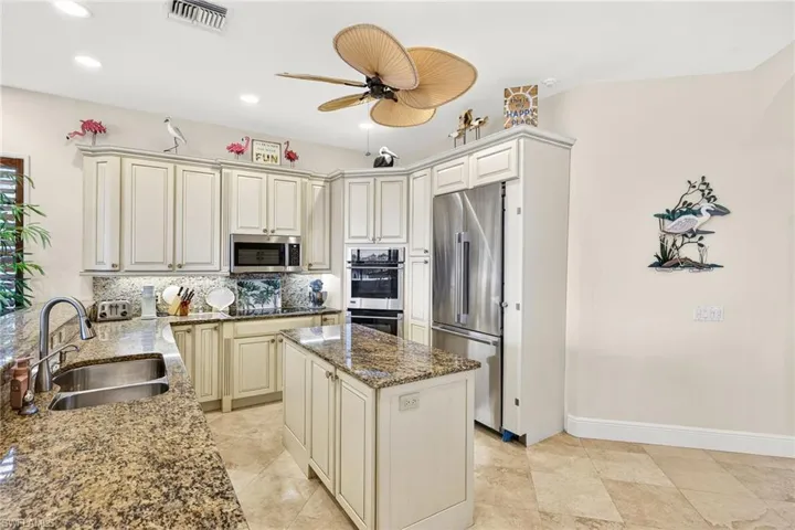 Kitchen with cream cabinets, dark stone counters, stainless steel appliances, backsplash, and recessed lighting