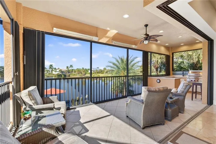 Sunroom / solarium with a ceiling fan, a water view, and an outdoor kitchen