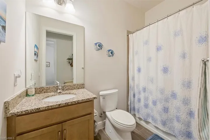 Second bathroom with tub shower and granite countertop vanity