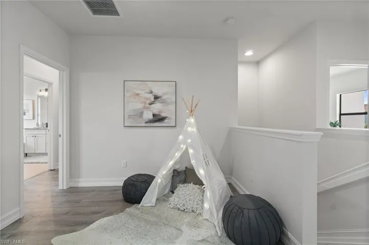 Loft area featuring wood finished floors and recessed lighting