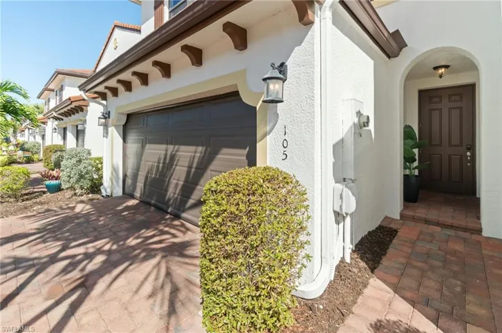 Tropical Property entrance with modern, bright scrub appeal, elegant paver driveway and walk up, and an attached 2 car garage.