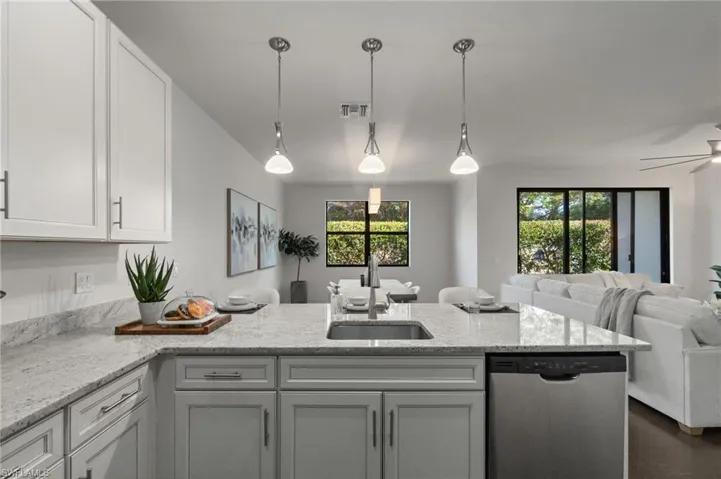 Modern kitchen with light granite countertops, stainless steel appliances and open sight lines to the main living area.