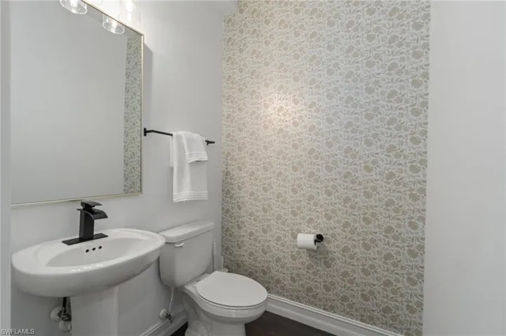 1st floor Half bathroom perfect for entertaining customized with wallpapered walls and dark wood-style flooring