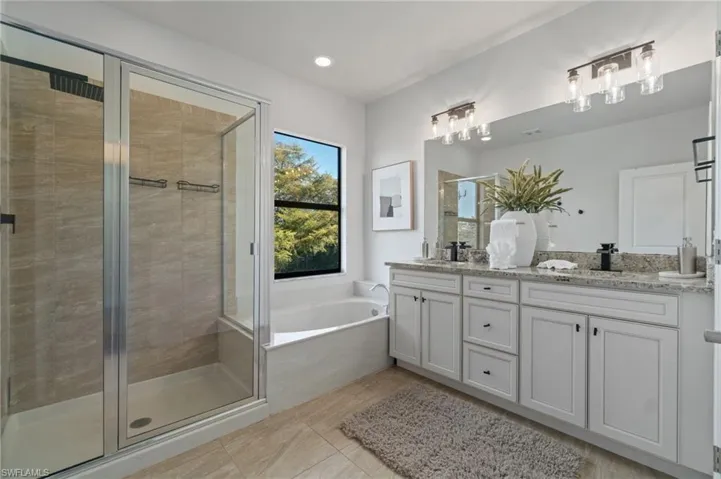 Full bath featuring double vanity, a stall shower, a bath, and recessed lighting
