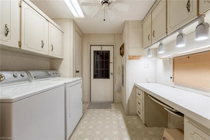Laundry room featuring washing machine and clothes dryer, a textured ceiling, ceiling fan, cabinet space, and light floors