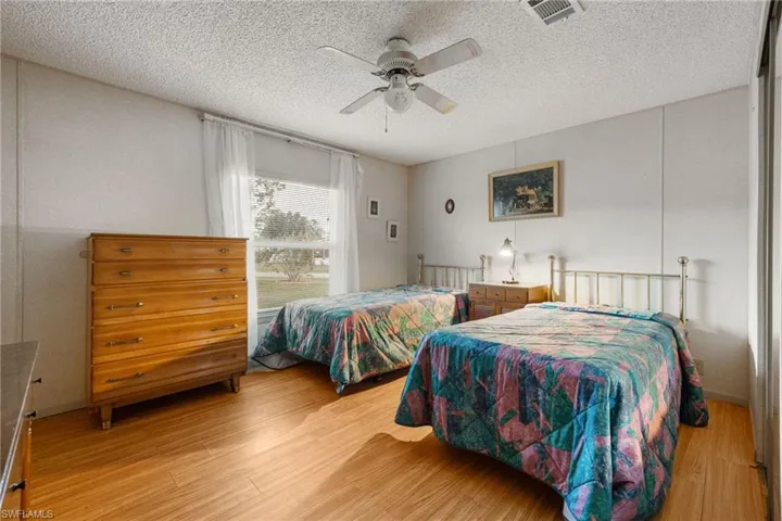 Bedroom with light wood-type flooring, a textured ceiling, and a ceiling fan
