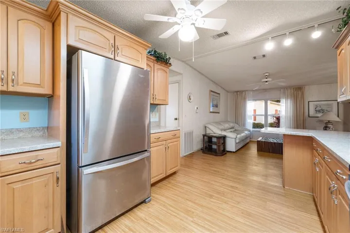 Kitchen featuring freestanding refrigerator, light wood-type flooring, open floor plan, a textured ceiling, and ceiling fan