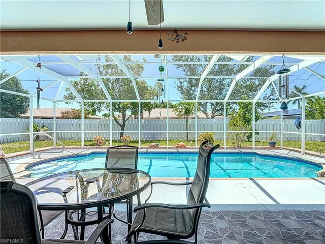 View of pool with screen enclosure and a patio