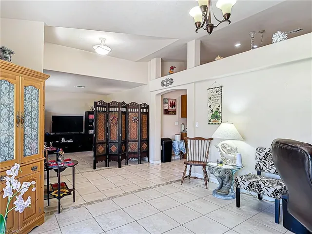 Sitting room with a notable chandelier, french doors, high vaulted ceiling, and light tile floors
