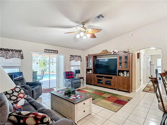 Living room with vaulted ceiling, ceiling fan, and light tile floors