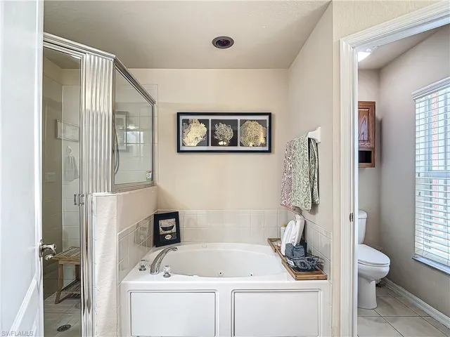 Bathroom featuring independent shower and bath, tile flooring, and toilet
