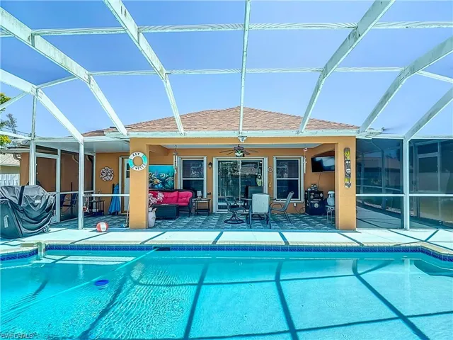 View of swimming pool with a patio area, glass enclosure, ceiling fan, and an outdoor living space