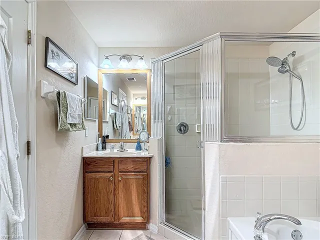 Bathroom with tile flooring, vanity with extensive cabinet space, and separate shower and tub