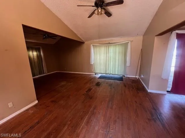 Empty room with ceiling fan, dark hardwood / wood-style flooring, and a textured ceiling