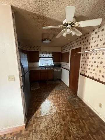 Kitchen featuring ceiling fan, dishwasher, fridge, and sink
