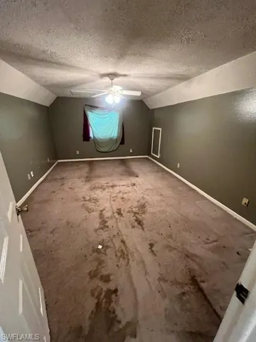 Bonus room with vaulted ceiling, carpet flooring, and a textured ceiling