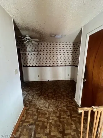 Hall featuring dark parquet floors and a textured ceiling
