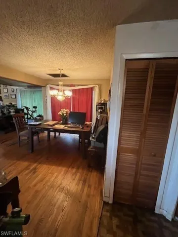 Dining area with a chandelier, dark hardwood / wood-style flooring, and a textured ceiling
