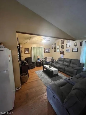 Living room featuring hardwood / wood-style flooring, ceiling fan, and lofted ceiling