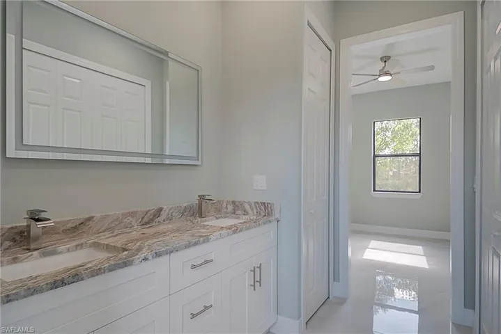 Bathroom featuring a closet, double vanity, and ceiling fan