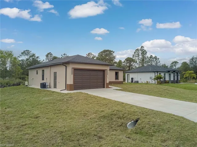 Ranch-style house featuring a front lawn, driveway, stucco siding, and an attached garage