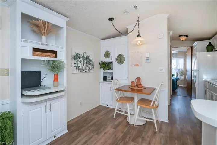 Dining room featuring a textured ceiling, dark wood finished floors, and ornamental molding