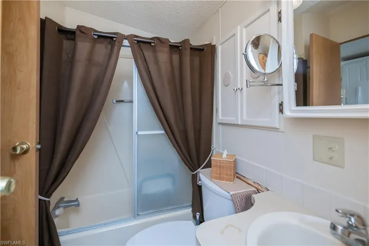Full bathroom featuring a textured ceiling, shower / bath combo with shower curtain, and vanity