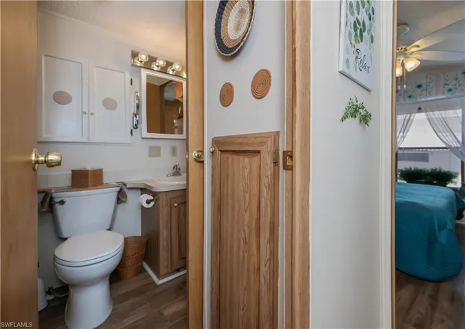 Half bath with vanity, dark wood-style floors, ensuite bath, and ceiling fan