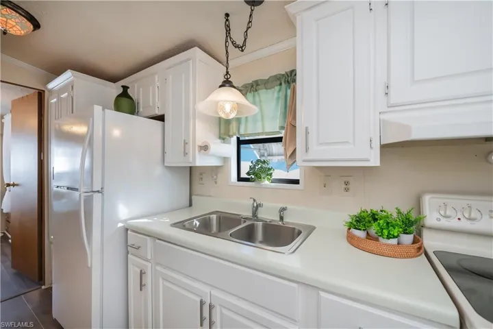 Kitchen with white appliances, white cabinets, and ornamental molding